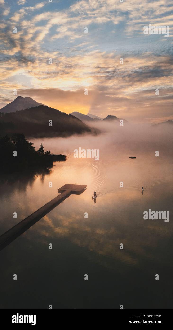 SUP - sali a pagaia all'alba e nelle mattine nebbiose sul Fuschlsee autunnale nella regione Salzkammergut di Salisburgo. Foto Stock