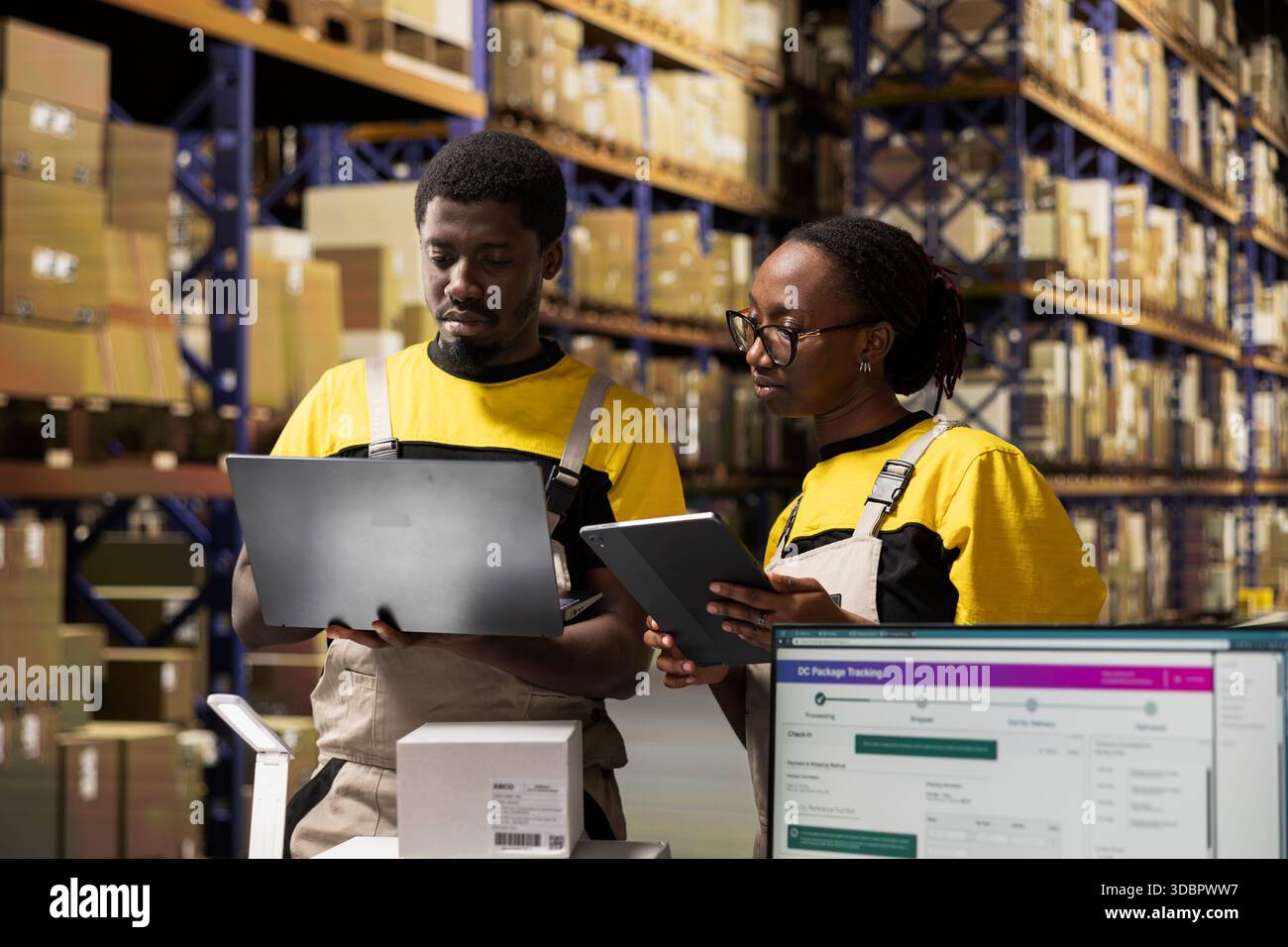 Dipendenti afroamericani che lavorano all'elaborazione degli ordini con i dispositivi, il centro di evasione degli ordini garantisce un flusso di lavoro efficiente. Gestione dei dati relativi ai pacchi per la consegna rapida. Logistica degli acquisti online. Foto Stock