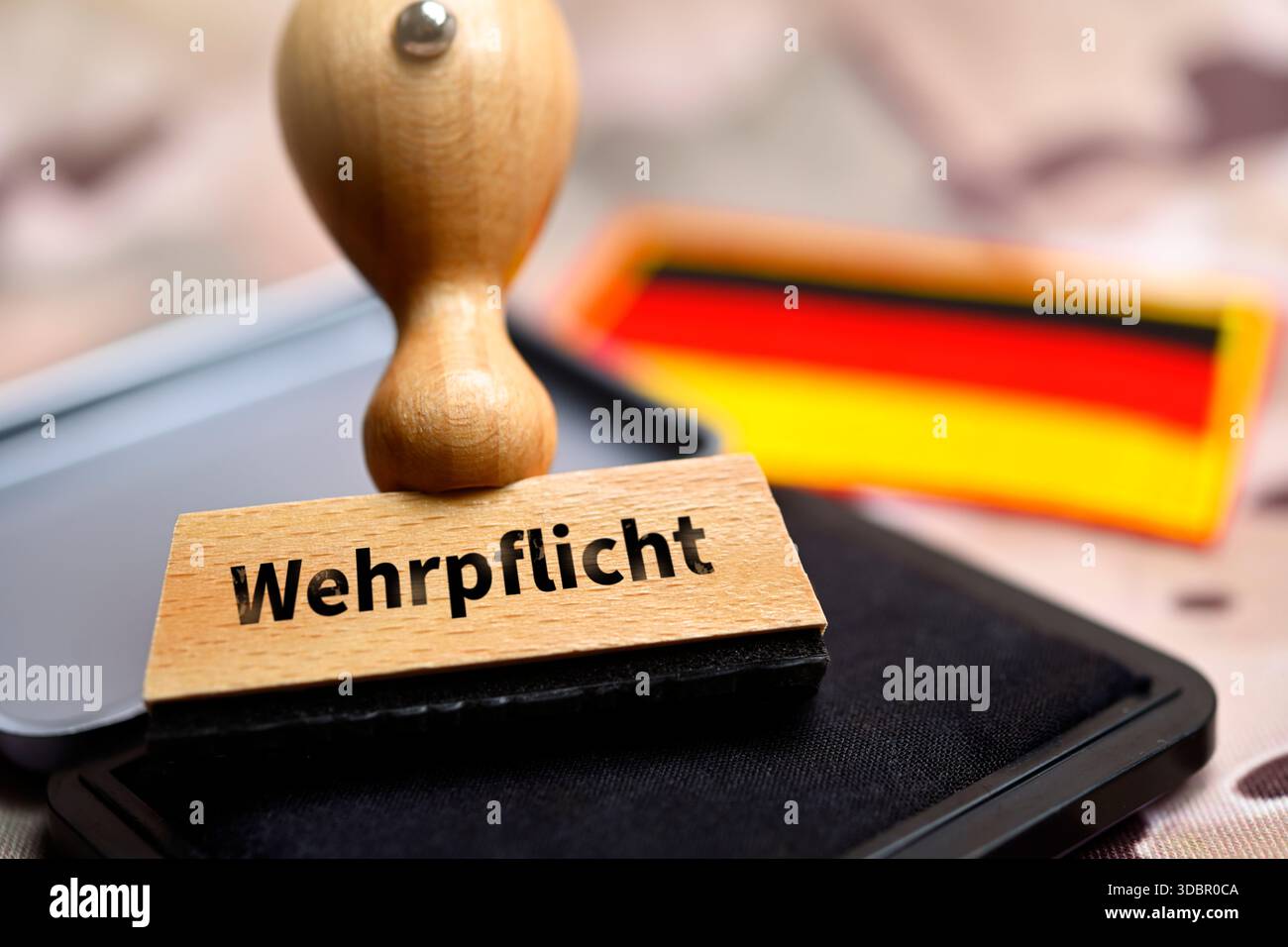 Timbro con la scritta "Wehrpflicht" davanti alla bandiera tedesca su un modello mimetico, fotomontaggio Foto Stock