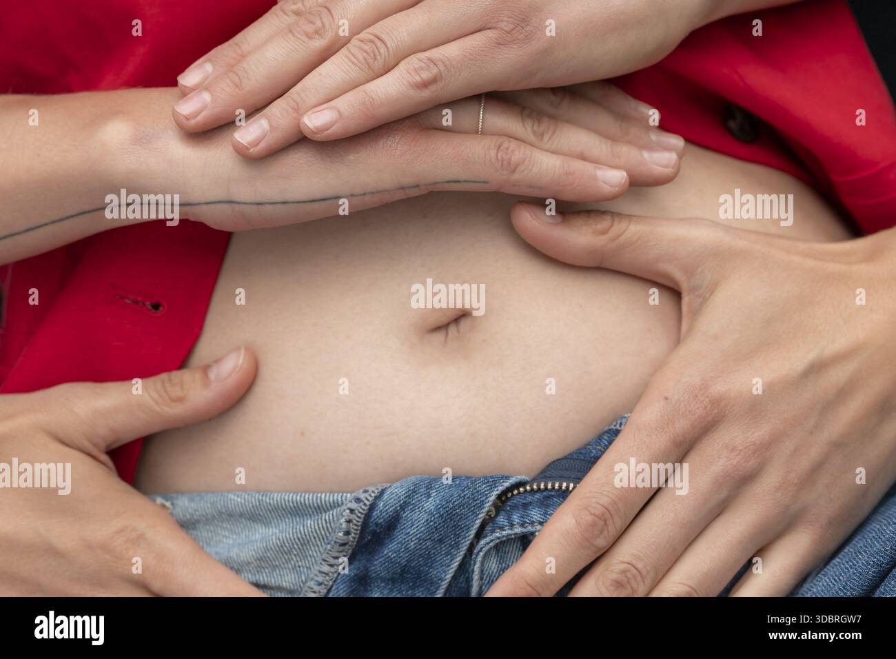 Immagine simbolica della gravidanza, mani stese sullo stomaco di una donna Foto Stock