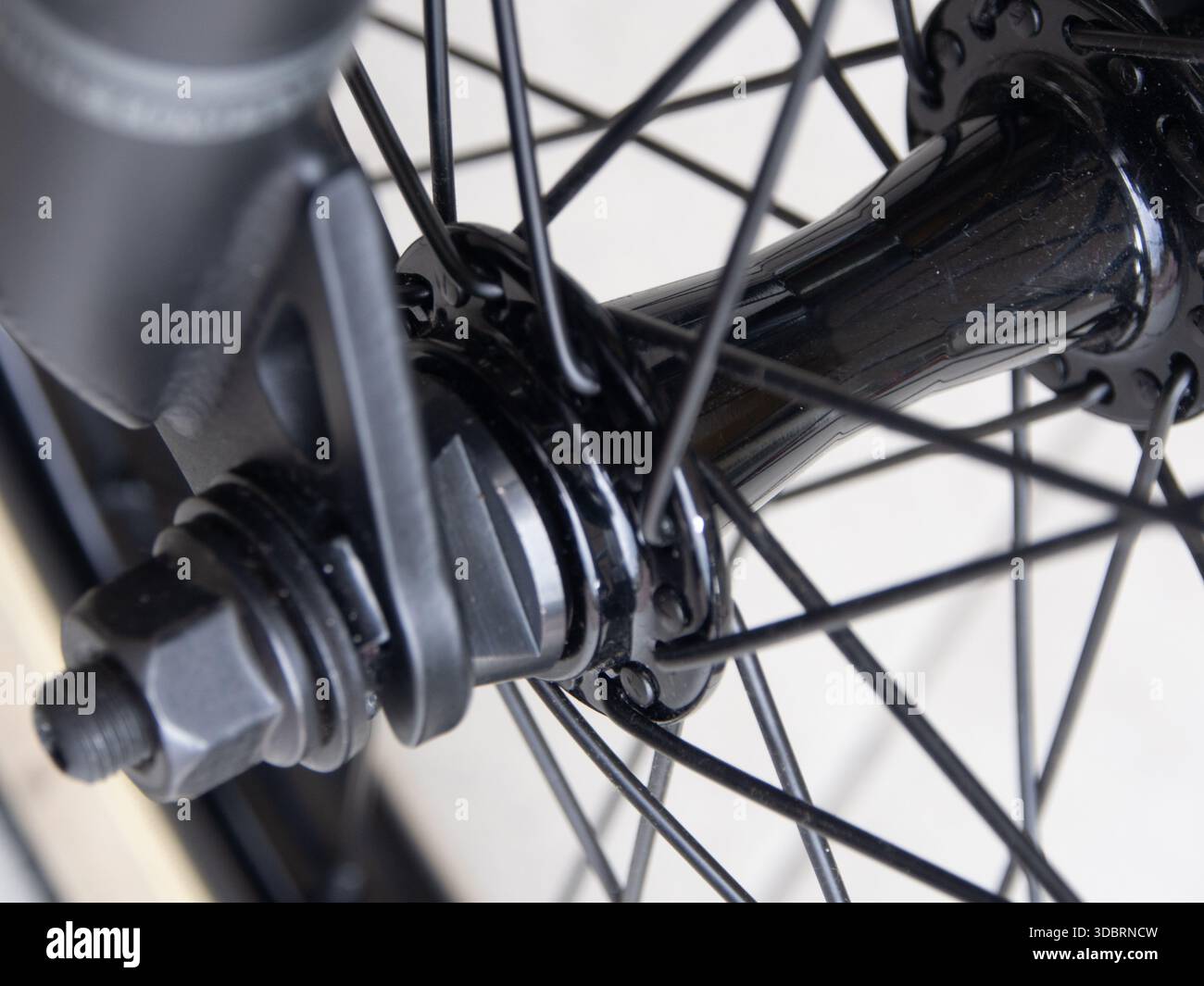 Primo piano del mozzo di una ruota di una bicicletta in nero con raggio del cerchio della ruota e una sezione della forcella. Foto Stock