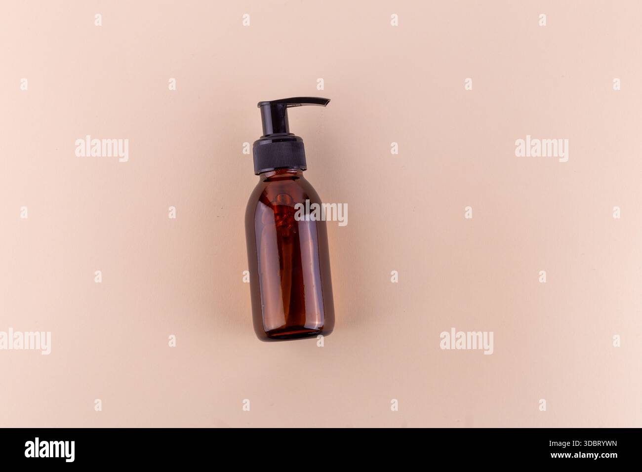 Flacone in vetro ambrato su sfondo beige. Foto Stock