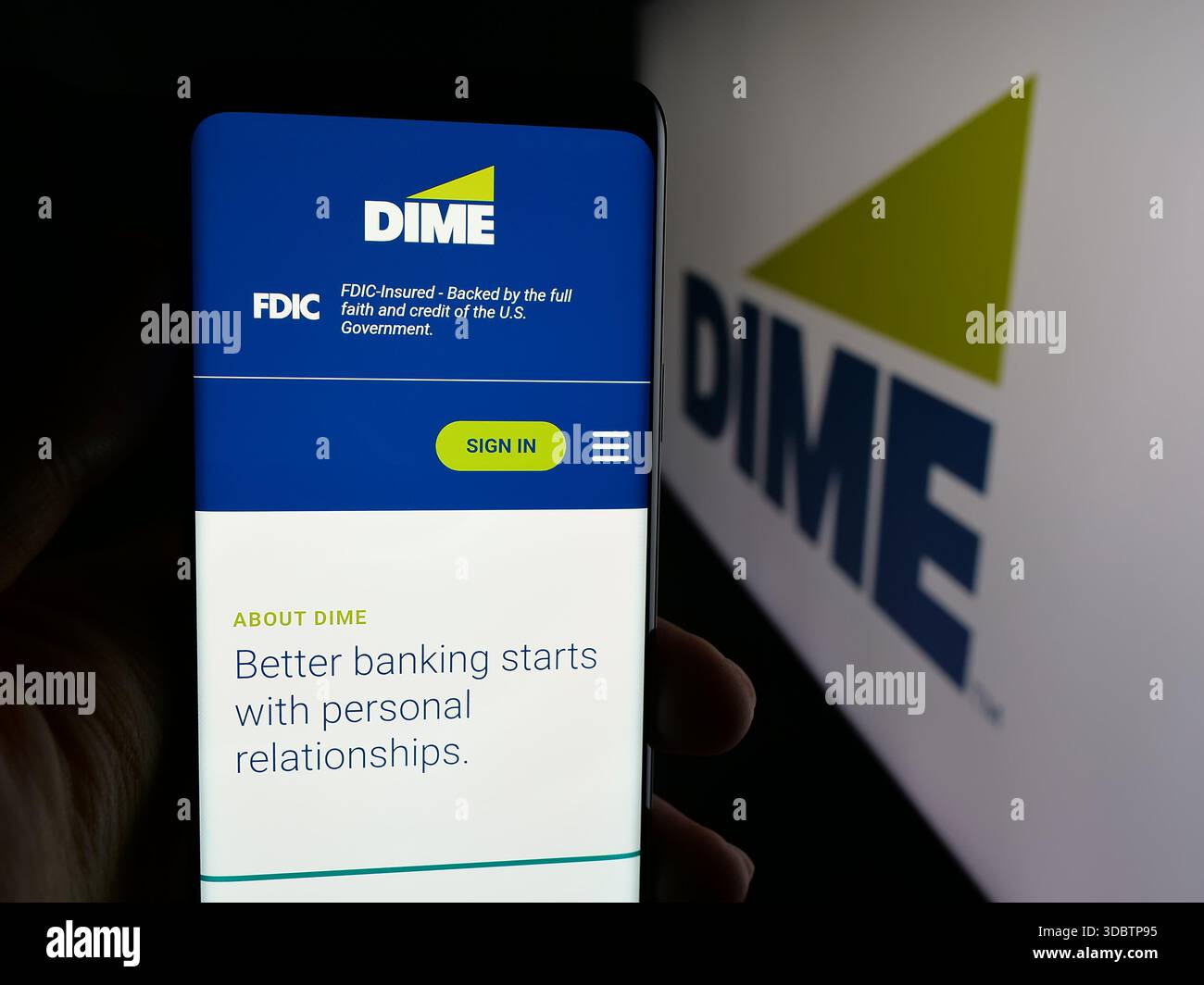 Stoccarda, Germania - 12-05-2025: Persona che detiene il cellulare con pagina web della società finanziaria statunitense DIME Community Bank sullo schermo davanti al logo. Foto Stock