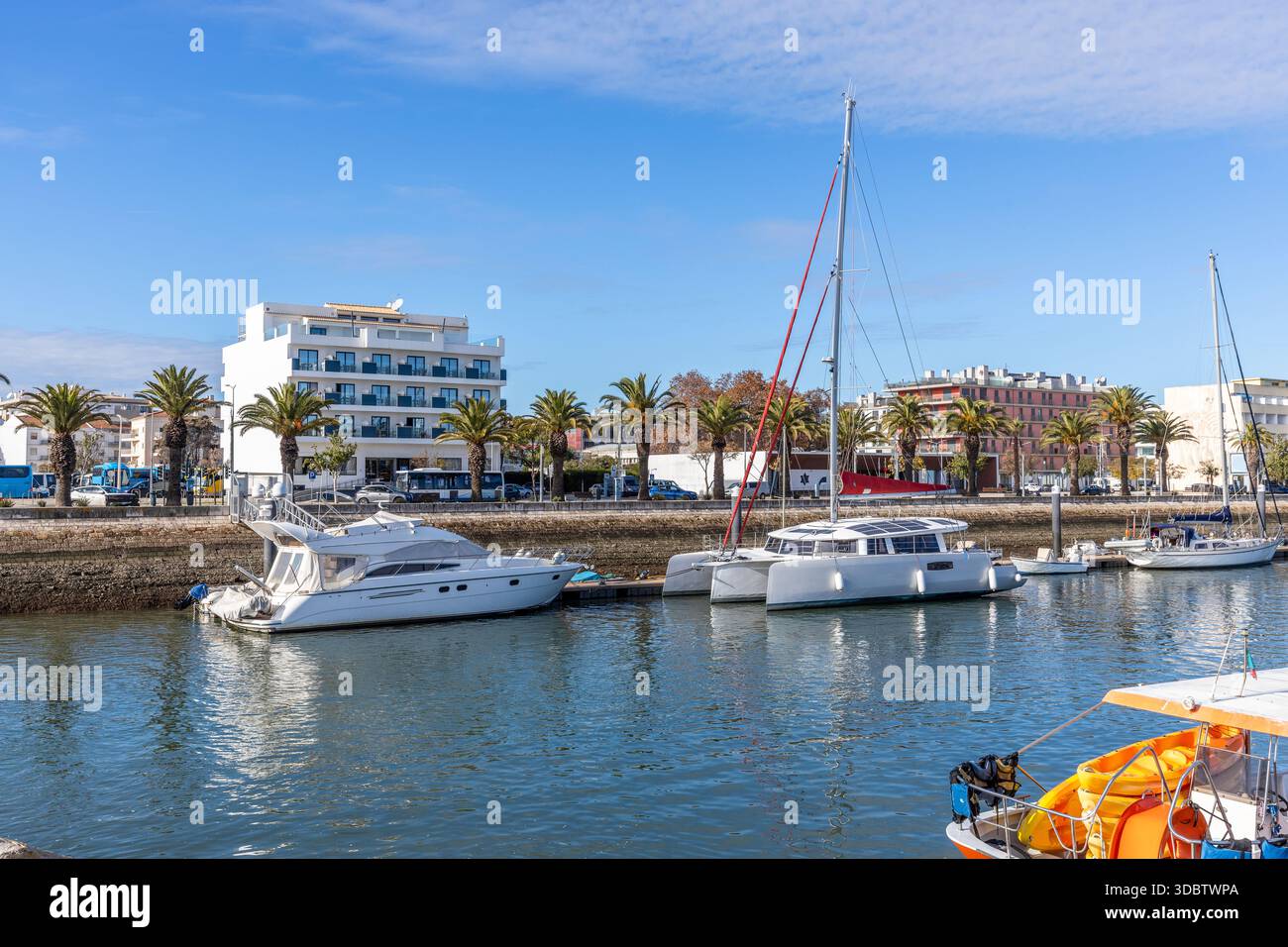 Vista soleggiata del porticciolo di Lagos, Algarve, Portogallo, con numerosi yacht e barche attraccate su acque calme e moderni edifici sul lungomare Foto Stock