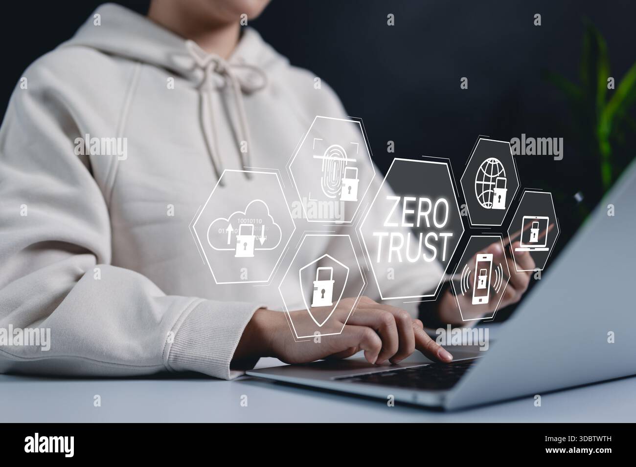 Concetto di sicurezza zero trust. Una donna che utilizza un notebook con un'interfaccia digitale icone di sicurezza Zero Trust, che simboleggiano la cybersicurezza, la protezione dei dati e un Foto Stock
