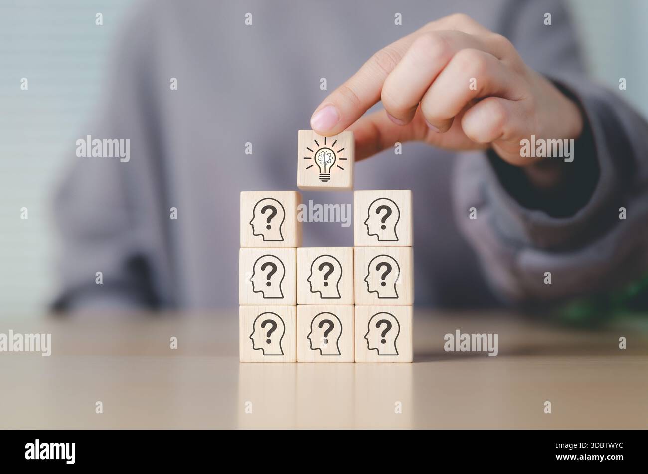 Pensiero creativo e concetto di problem solving. Impilare a mano blocchi di legno con punti interrogativi, posizionare il blocco finale con lampadina illuminata. probl Foto Stock