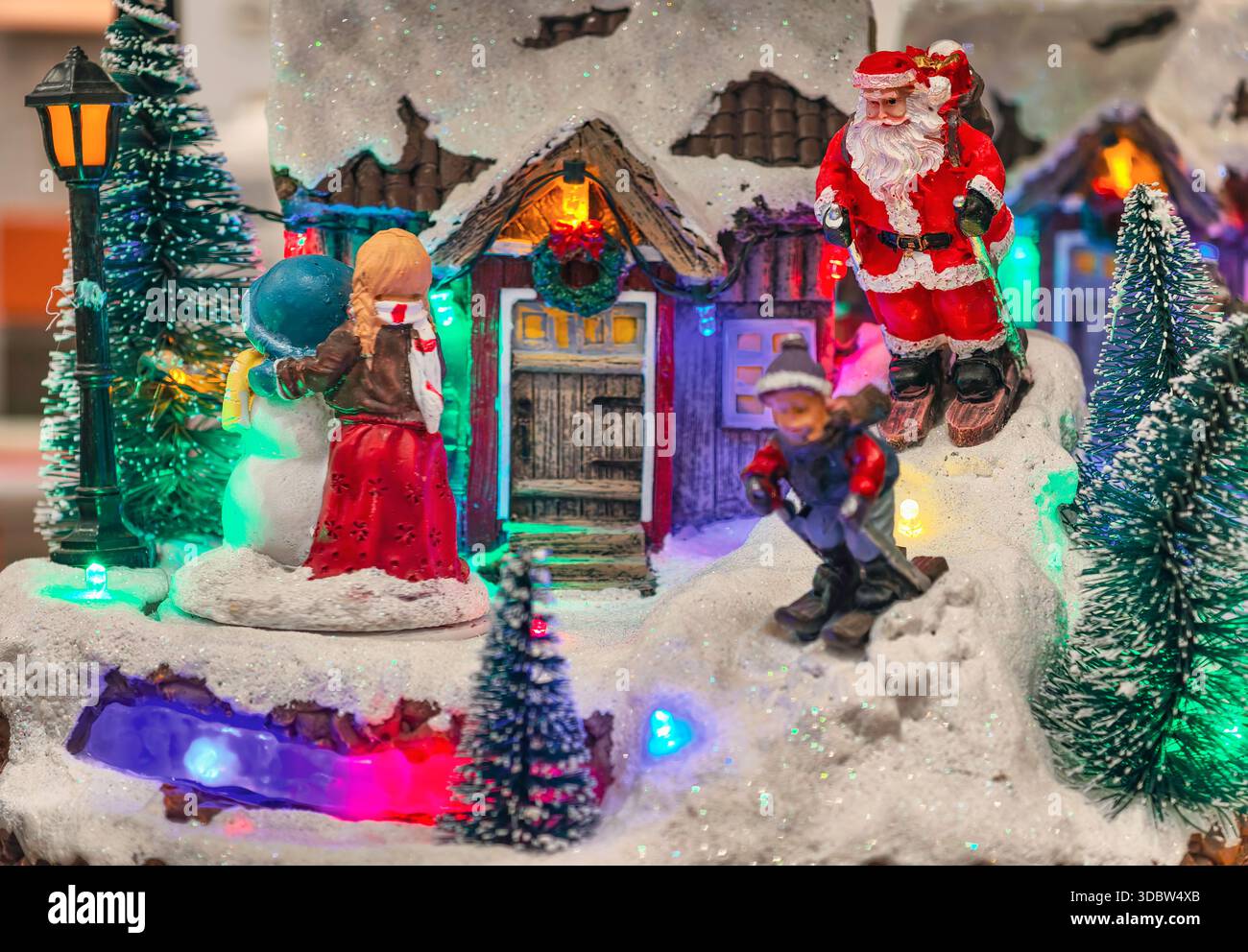 Scena in miniatura del villaggio di Natale con le statuine di Babbo Natale, case illuminate, esposizione delle decorazioni natalizie, festività, sfondo di Capodanno Foto Stock