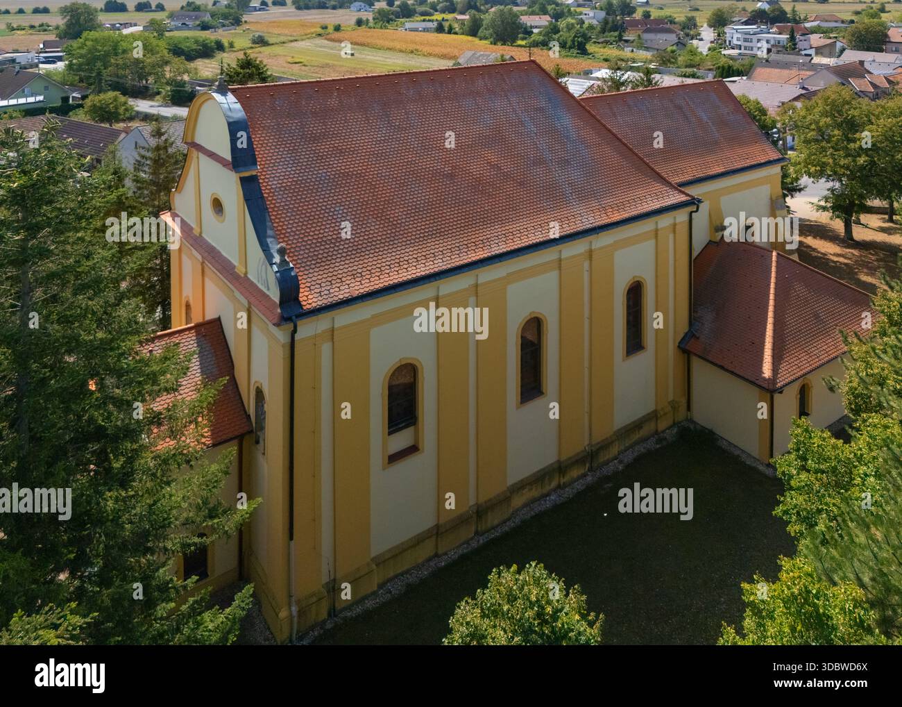 Veduta aerea della Chiesa di tutti i Santi con la sua facciata color crema e giallo e il tetto con tegole rosse che si erge maestosamente tra la lussureggiante vegetazione, Lab, Bratis Foto Stock