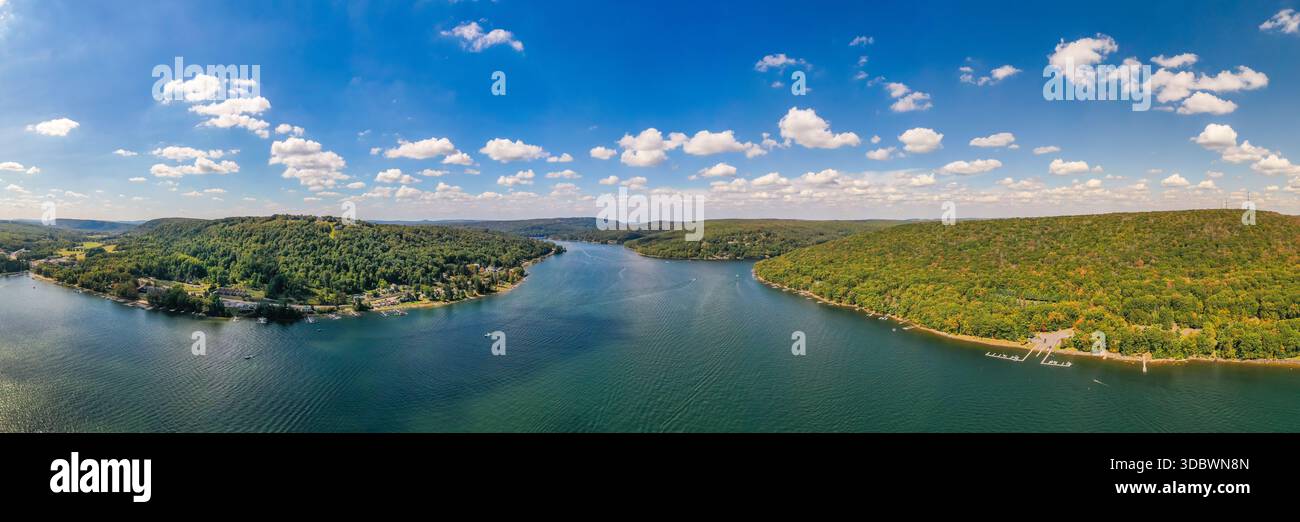 Vista aerea delle acque blu che si snodano tra colline verdeggianti ricoperte di alberi sotto un cielo luminoso e punteggiato di nuvole, Deep Creek, Maryland, USA. Foto Stock