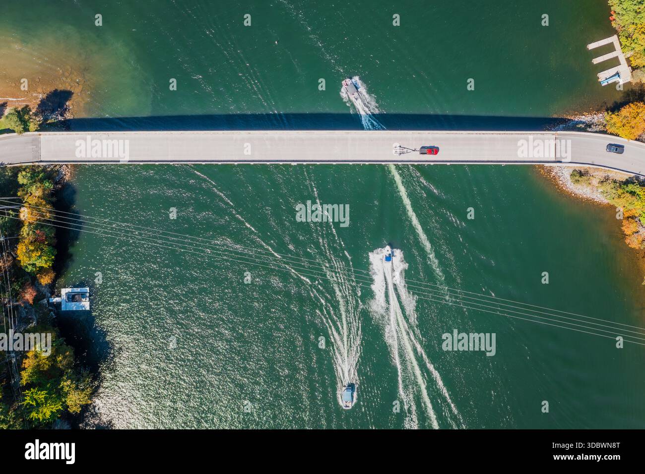 Vista aerea del ponte sul lago Deep Creek, dove le barche intagliano il bianco si sveglia attraverso le acque verde scuro sotto un cielo luminoso, Deep Dreek, Maryland, Foto Stock