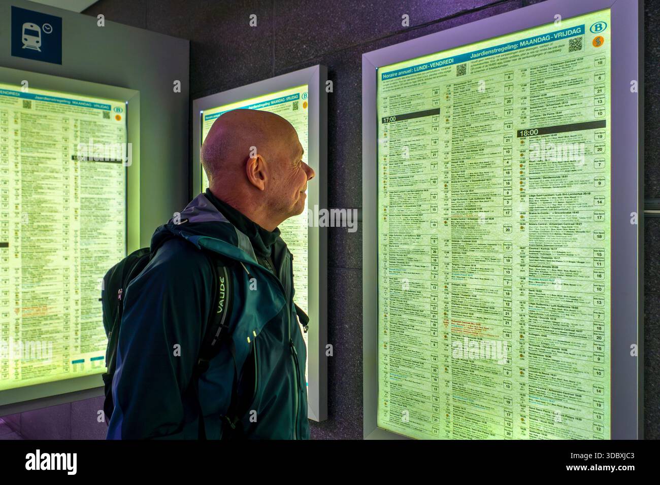 Viaggiatore/pendolare che guarda le partenze dei treni negli orari della stazione ferroviaria NMBS Bruxelles-Sud / Gare de Bruxelles-Midi a Bruxelles, Belgio. Mod Foto Stock