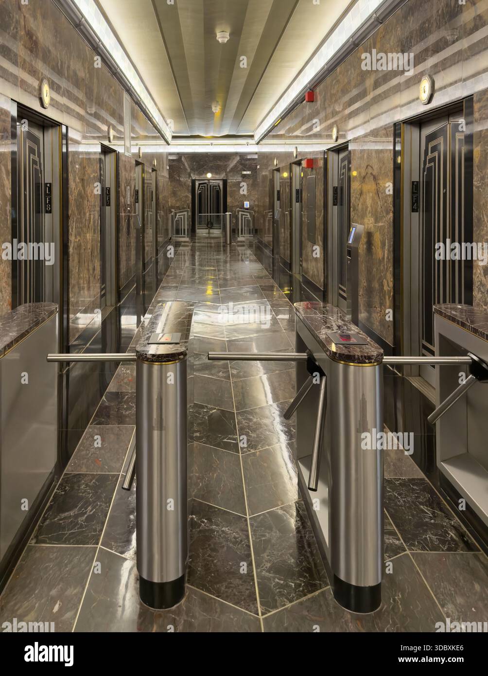 Vista dei tornelli metallici e delle pareti in marmo di un corridoio dell'edificio, che riflettono la luce in un motivo simmetrico, New York, New York, Stati Uniti. Foto Stock