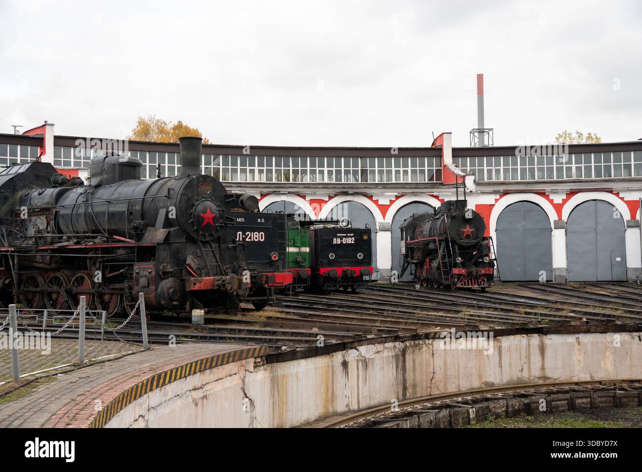 Mosca, Russia - 18 ottobre 2025: Locomotive a vapore dell'epoca sovietica esposte su un giradischi ferroviario presso il museo Povorotny Krug, archi della roundhouse Foto Stock