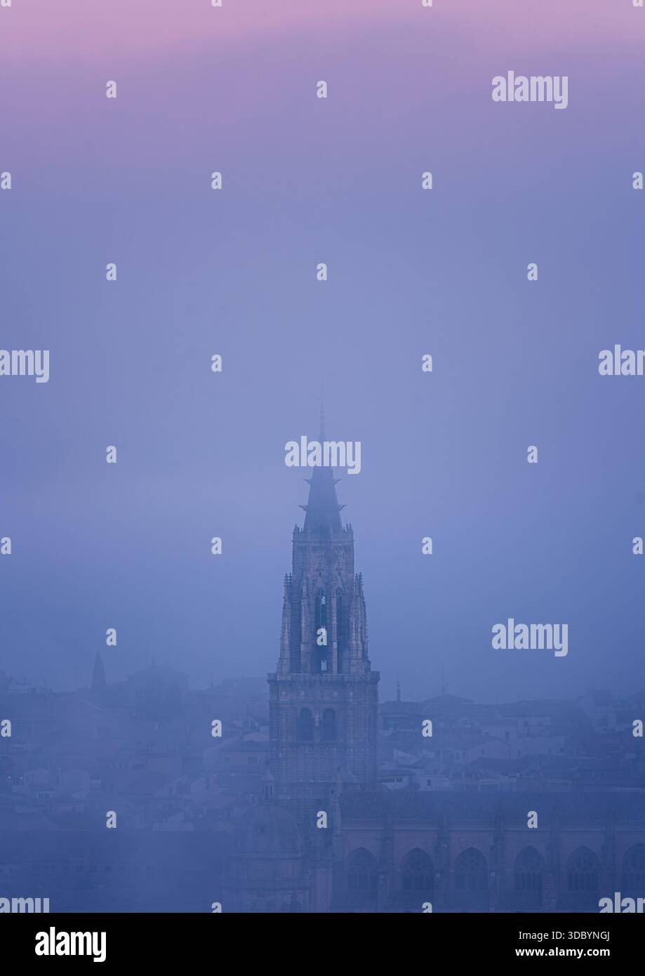 Vista verticale della guglia della cattedrale di Toledo che emerge dalla fitta nebbia mattutina. Composizione minimale e tonalità pastello tranquille. Foto Stock