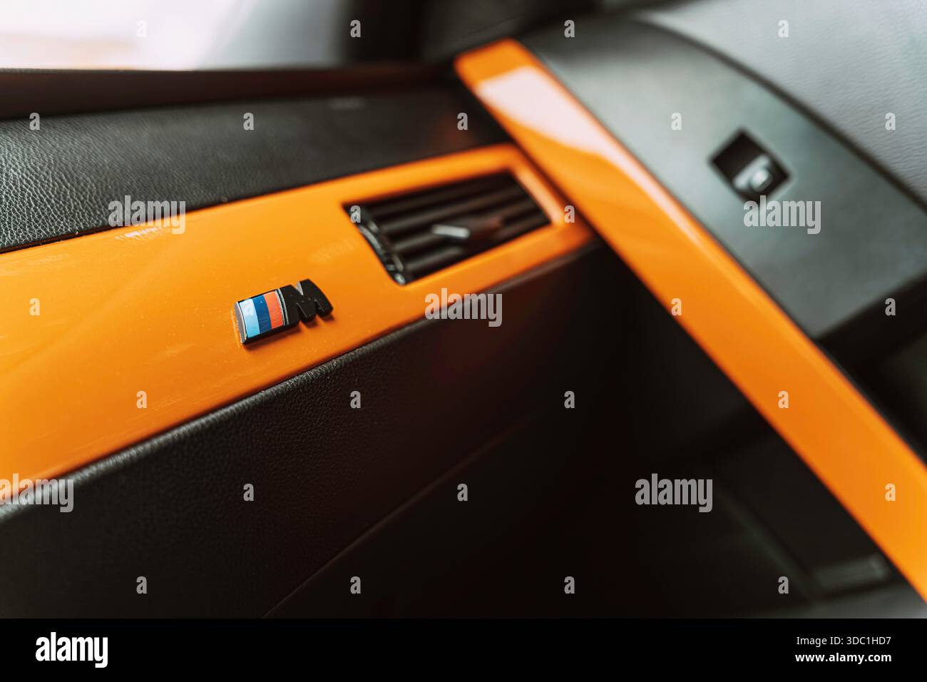 Rovigo, italia 18 dicembre 2025: Primo piano degli interni bmw serie m con dettagli arancioni sul cruscotto, iconico logo m e prese d'aria sportive per un tocco di lusso Foto Stock