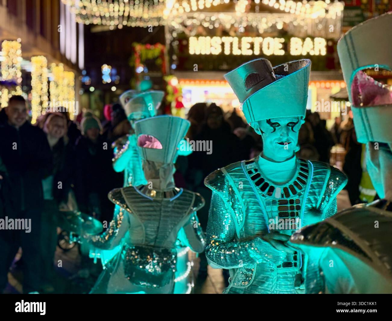 SCINTILLA! Batteristi LED che si esibiscono in un evento natalizio a Princesshay, Exeter, con costumi brillanti e luci festive vicino al Mistletoe Bar. - Immagine stock catturata con smartphone