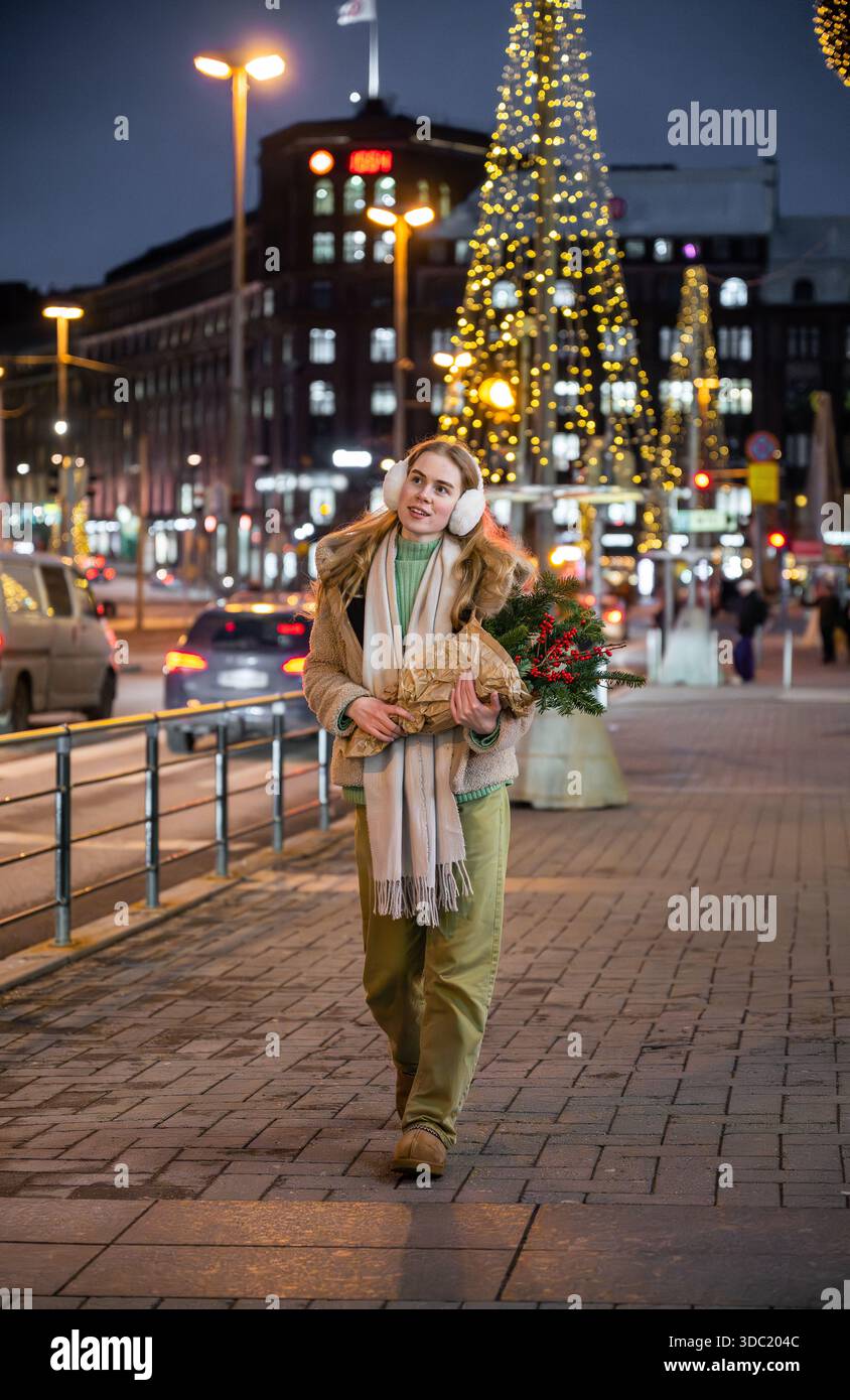 Donna che cammina sulla strada di Natale con decorazioni natalizie a Helsinki Foto Stock