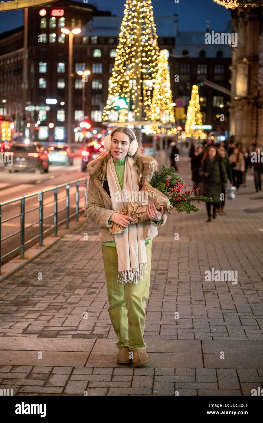 Donna che cammina sulla strada di Natale con decorazioni natalizie a Helsinki Foto Stock