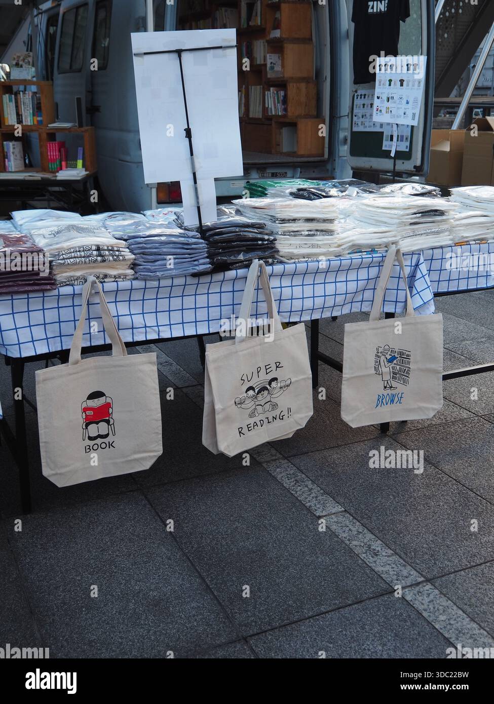 Stand di merchandising all'aperto per la fiera del libro d'arte con borse e libri a Tokyo Foto Stock