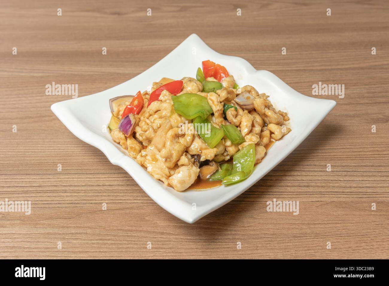 Pollo Kung Pao con peperoni rossi e verdi a dadini, arachidi e anacardi, con una salsa dolce e acida leggermente ispessita, servita sopra gli spaghetti Foto Stock