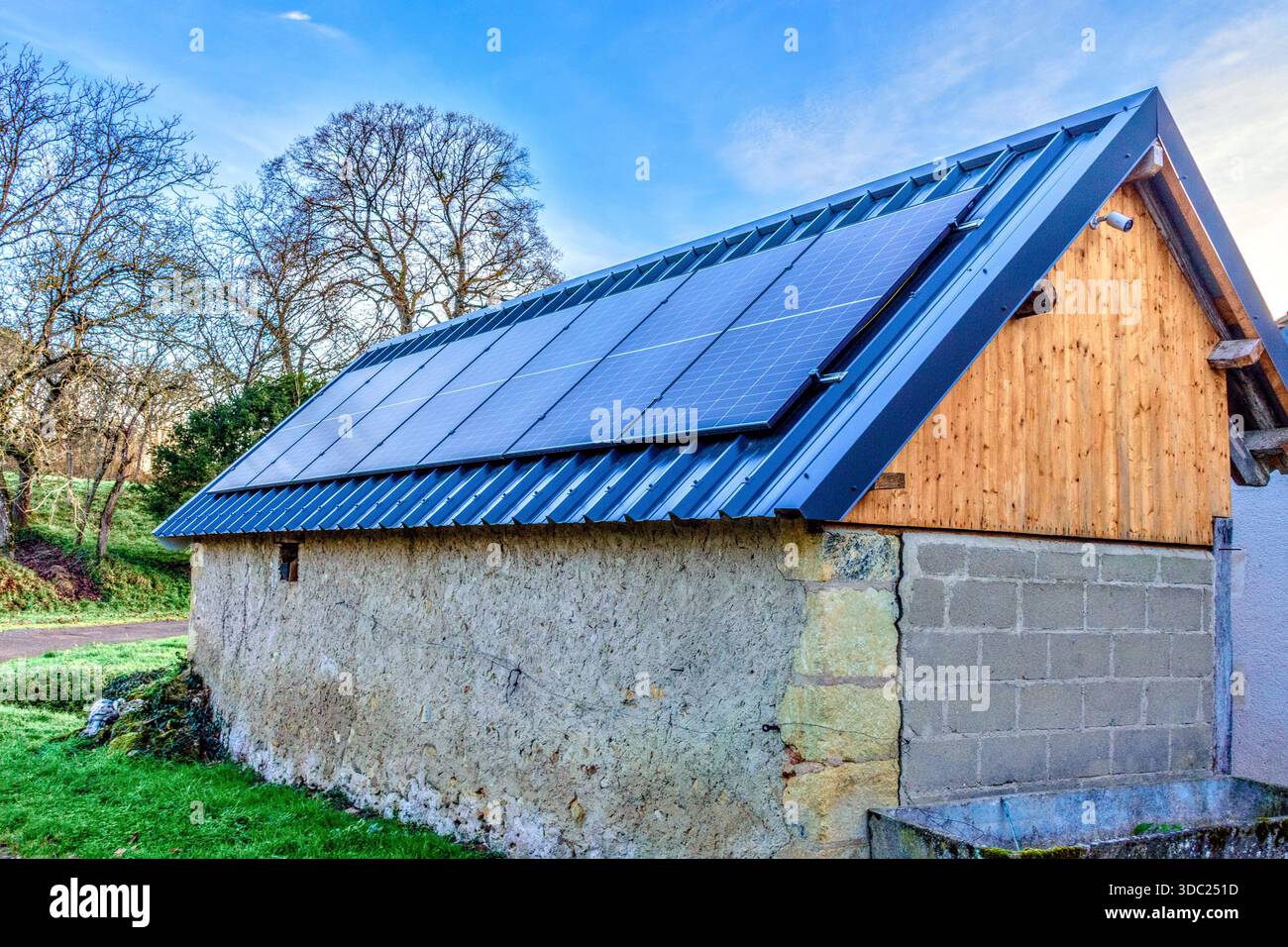 Nuovi pannelli solari e nuovo tetto in metallo ondulato in un edificio agricolo ristrutturato - Francia centrale. Foto Stock