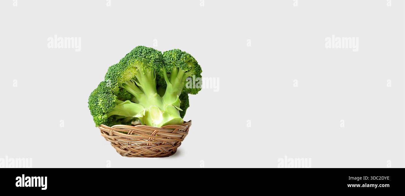 Testa di broccoli isolata su sfondo luminoso. Broccoli in un cestello di legno. Foto in studio, minimalismo, verdure crude verdi, fonte di vitamine Foto Stock