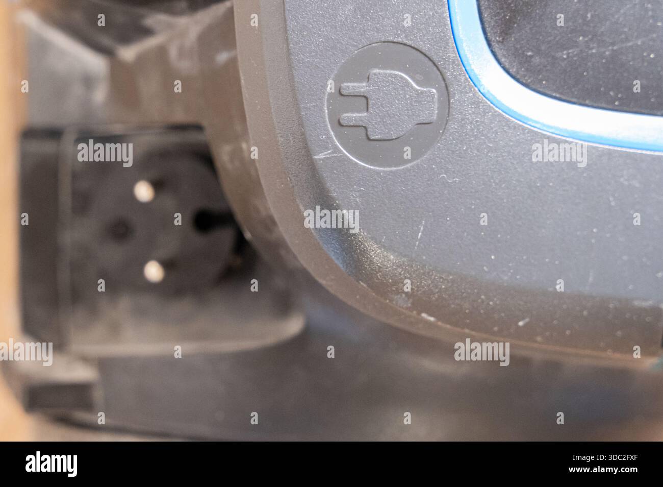 primo piano dell'ingresso di alimentazione del vuoto che mostra spina, denti incassati nella presa, polvere intorno al connettore, icona di sicurezza in rilievo, serracavo ed evidente usura Foto Stock