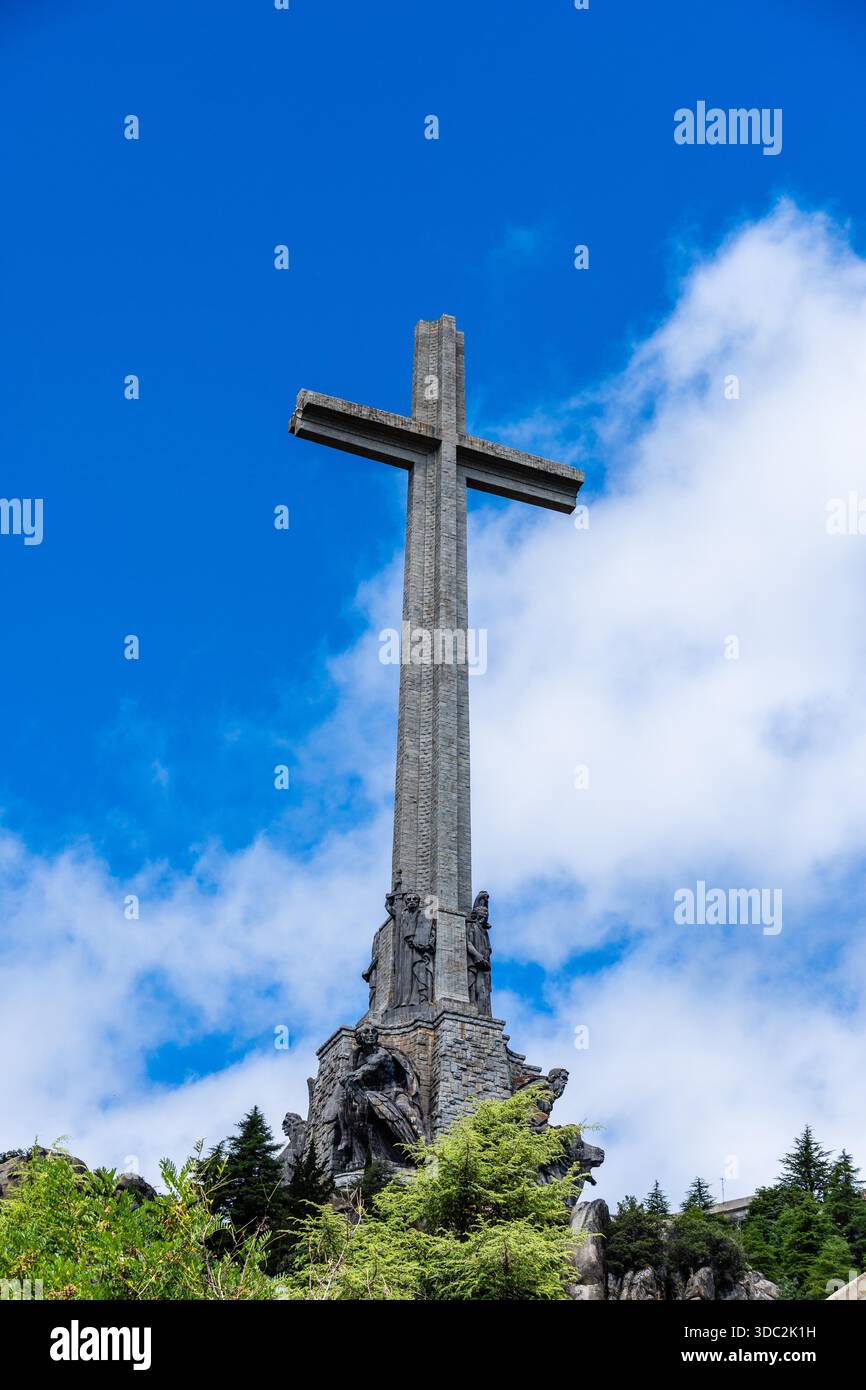 San Lorenzo de El Escorial, Spagna - 20 luglio 2025: Una suggestiva vista della Valle dei Caduti a El Escorial, Madrid, con la croce torreggiante contro un cielo nuvoloso. Foto Stock