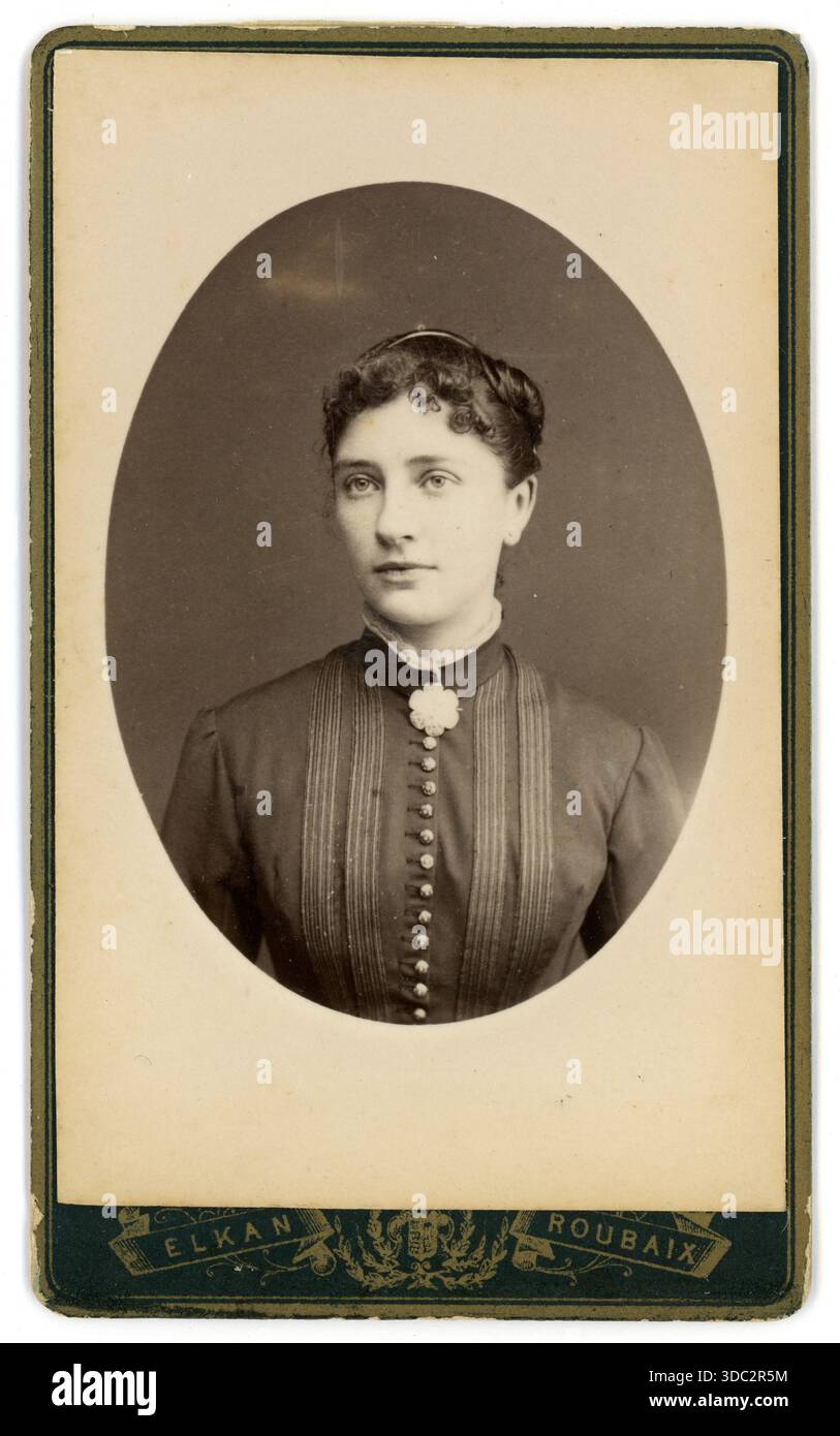 Originale carta de visite vittoriana (biglietto da visita o CDV): Ritratto ovale di una bella donna francese che indossa una spilla floreale, abbottonatura della camicetta o del vestito, frangia piegata o arricciata. Fotografia del fotografo olandese, Elkan (Jacob Huisman) 74, Rue Pellart, 59100 Roubaix, Francia, circa 1880 Foto Stock