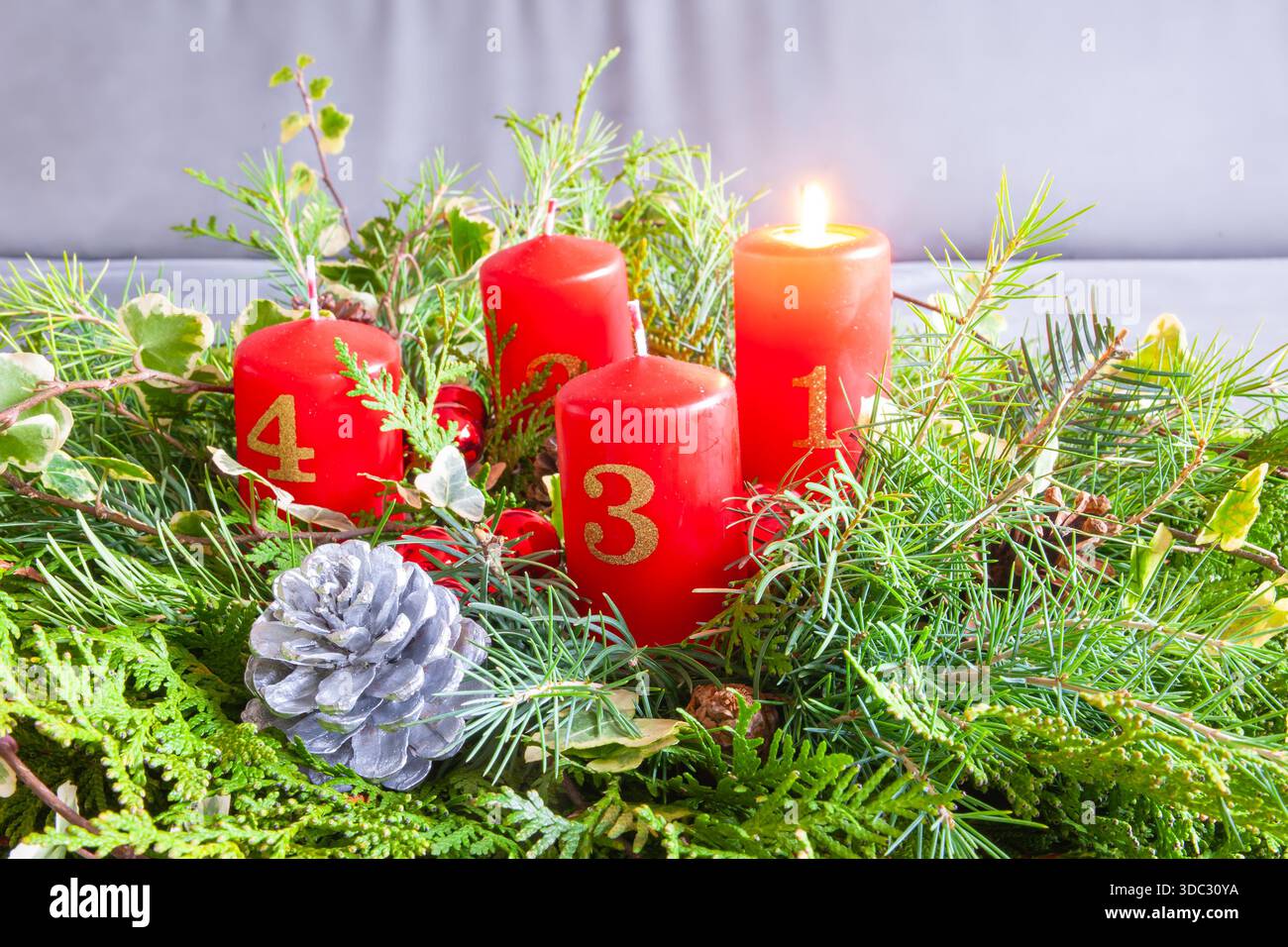 Corona dell'avvento natalizio con candele numerate rosse e fogliame sempreverde Foto Stock