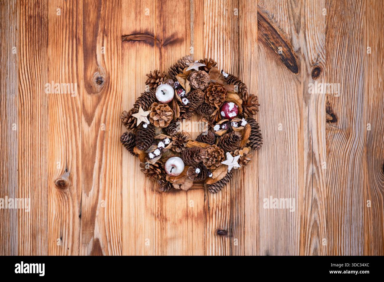 Corona decorativa appesa su una porta d'ingresso di un cottage in legno Foto Stock