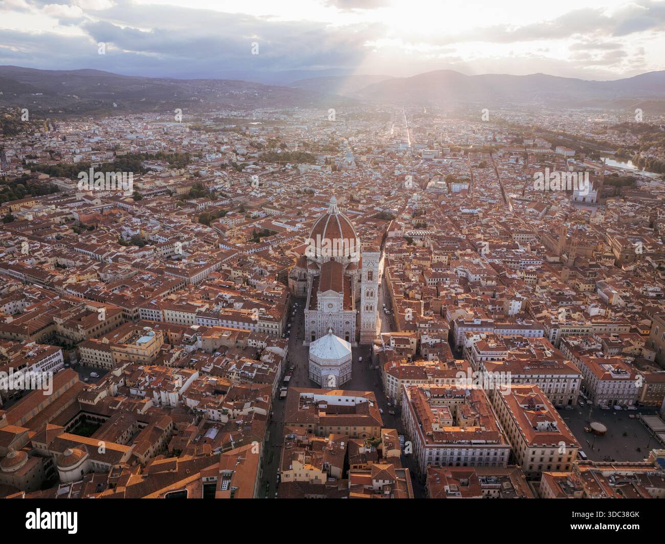 Vista aerea dell'iconico Duomo di Firenze che attraversa un mare di tetti in terracotta, bagnato dal caldo bagliore del sole che tramonta, Firenze, Toscana Foto Stock
