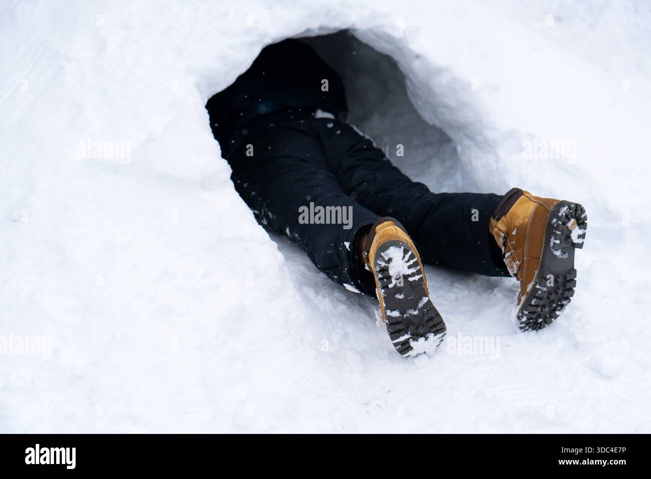 Persona parzialmente sepolta nella grotta della neve - solo le gambe visibili. Foto di alta qualità Foto Stock