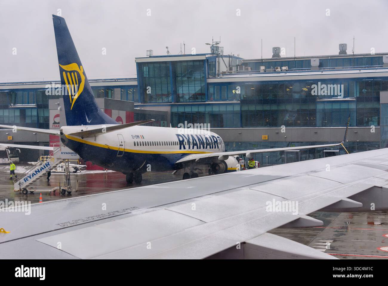 Ozarowice, Polonia - 23 novembre 2025: Una vista da un posto vicino al finestrino che guarda un aeromobile Ryanair Boeing 737 parcheggiato sull'asfalto bagnato di fronte al Foto Stock