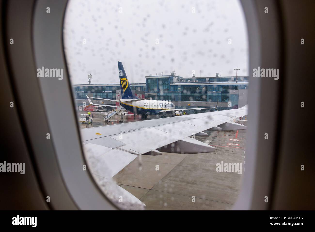 Ozarowice, Polonia - 23 novembre 2025: Una vista piovosa dalla finestra di un aereo che guarda un Boeing 737 Ryanair parcheggiato sull'asfalto bagnato a Katowice A. Foto Stock