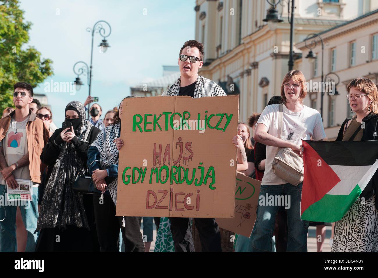 Folla di manifestanti che tengono in mano dei cartelli durante una marcia pro-Palestina vicino al cancello d'ingresso dell'Università di Varsavia. Foto Stock