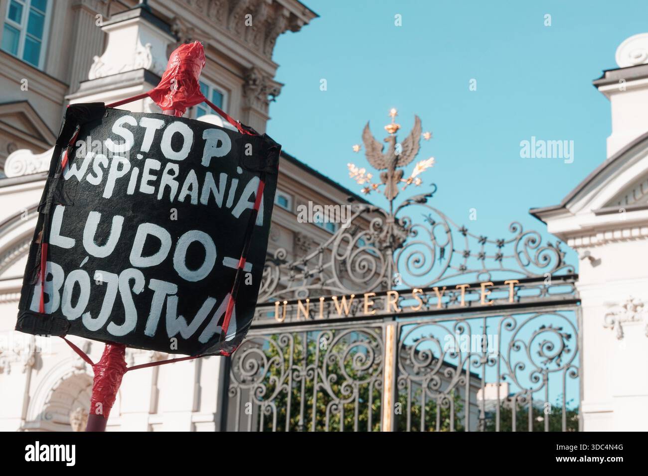 Segno di protesta che chiede di smettere di sostenere il genocidio durante una manifestazione pro-Palestina vicino alla porta dell'Università di Varsavia. Foto Stock