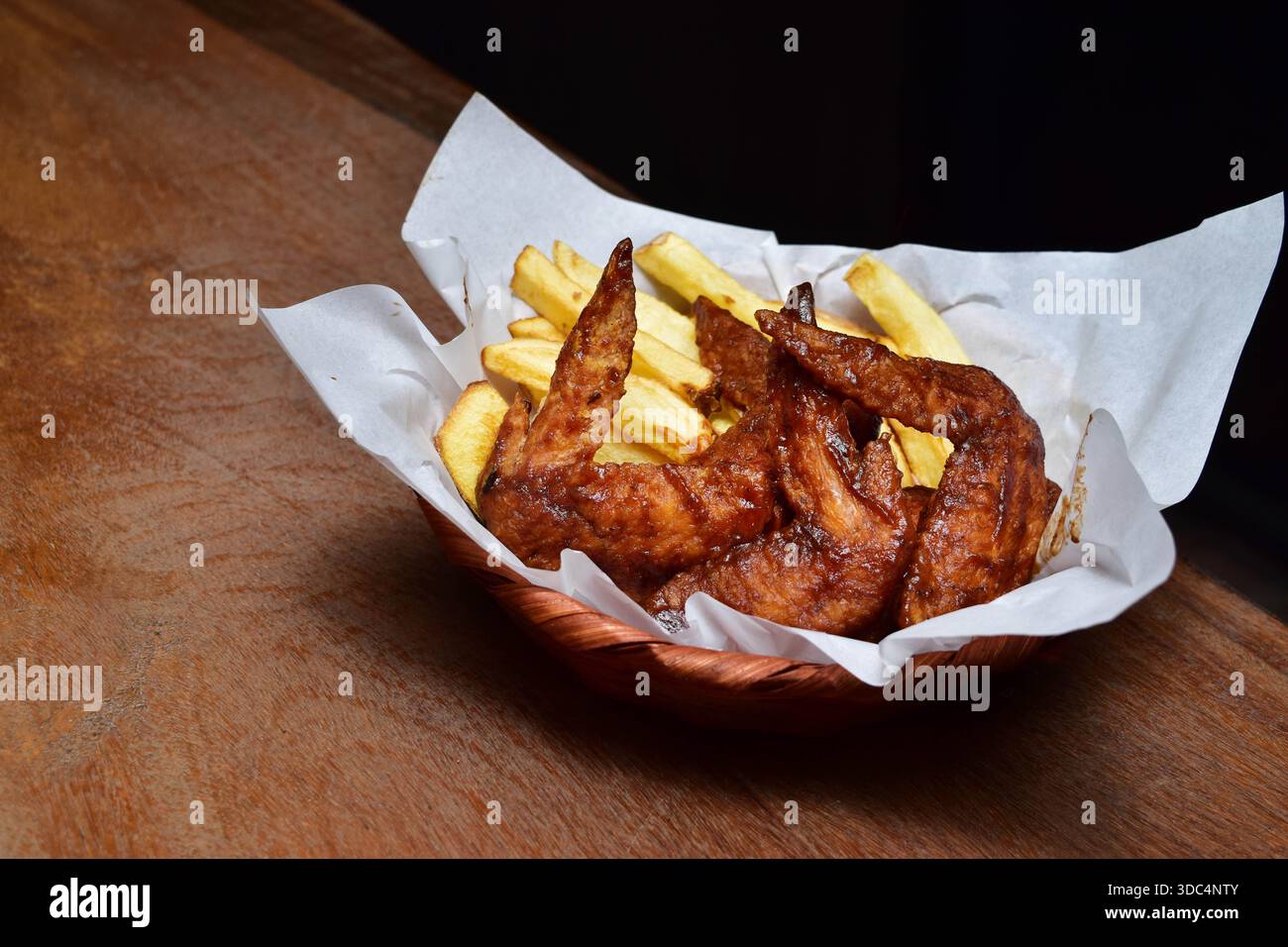 Cheeseburger di manzo e ali di pollo glassati con patatine fritte croccanti Foto Stock