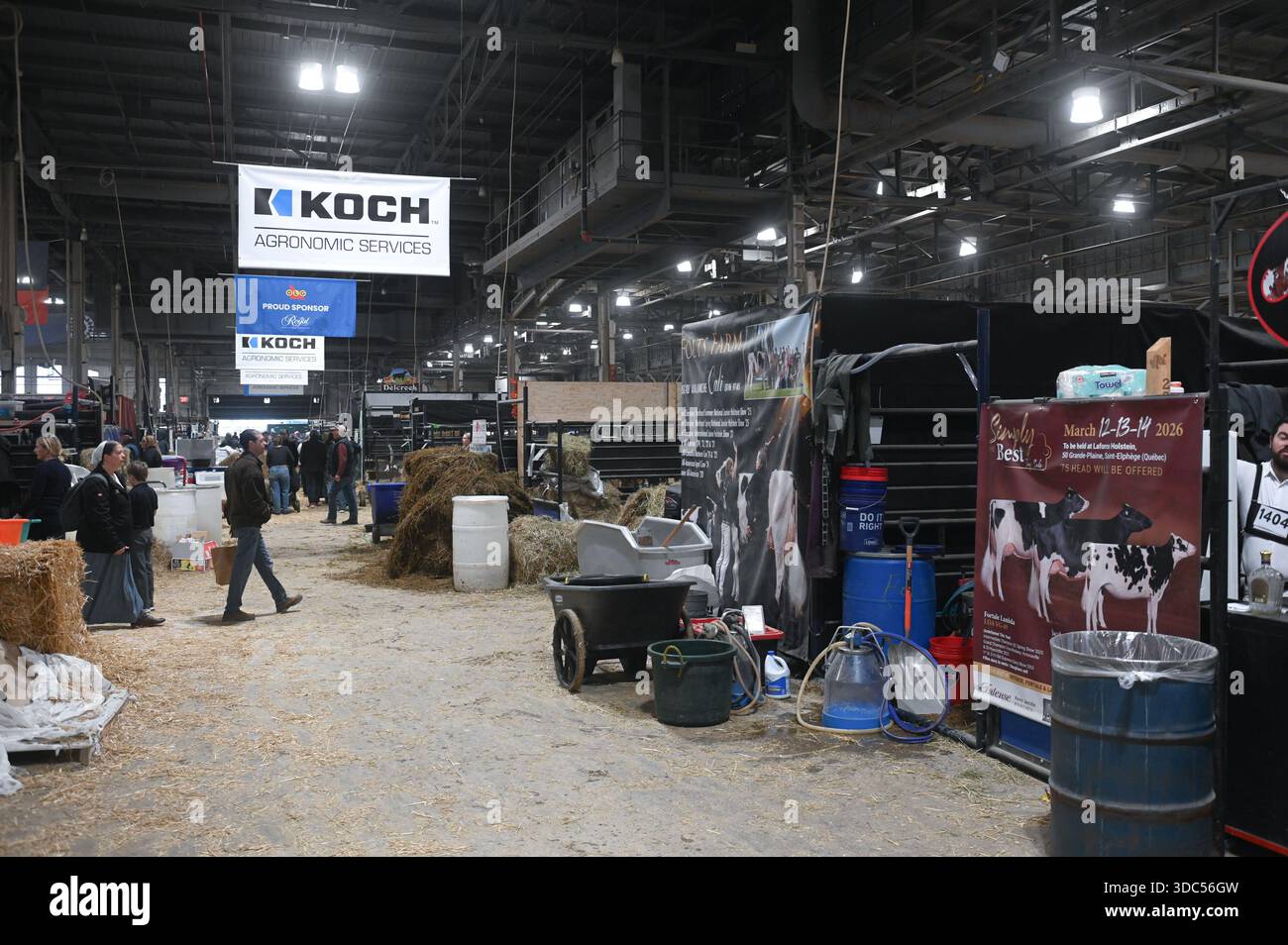 Toronto, ONTARIO, Canada - 14 novembre 2025: Persone che camminano intorno a una grande sala espositiva piena di fieno, attrezzature e striscioni per un fai agricolo Foto Stock
