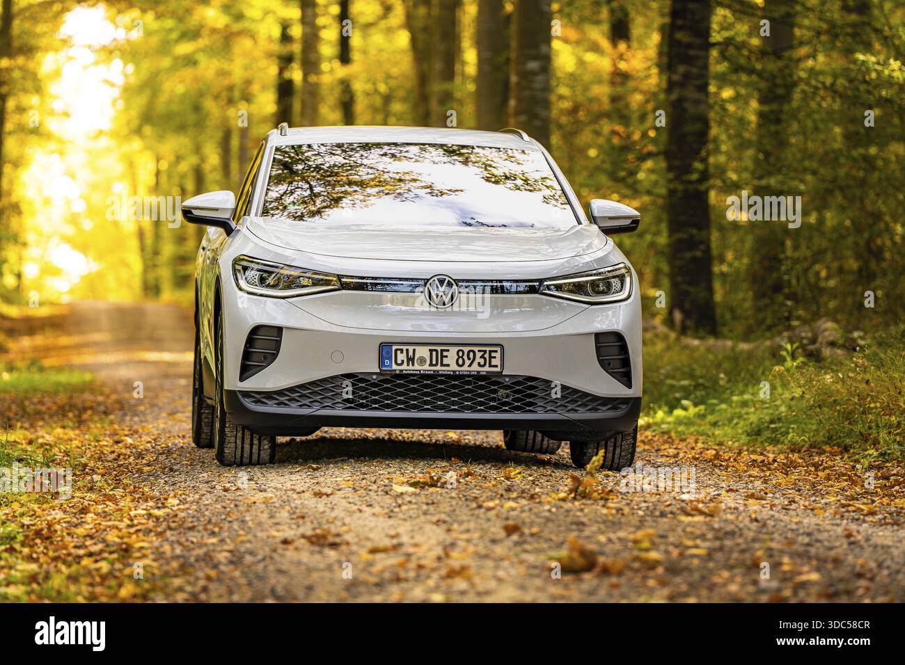 Auto bianca su una strada forestale autunnale, auto elettrica VW ID4, Deer Carsharing, Calw, Germania Foto Stock