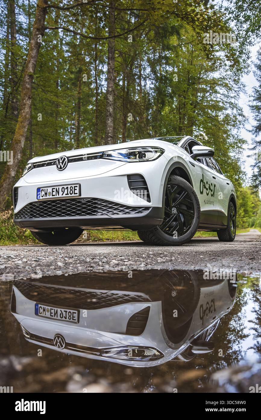 Un'auto bianca si riflette in un pozzo d'acqua su una strada forestale, l'auto elettrica VW ID4, Deer Carsharing, Calw, Germania Foto Stock