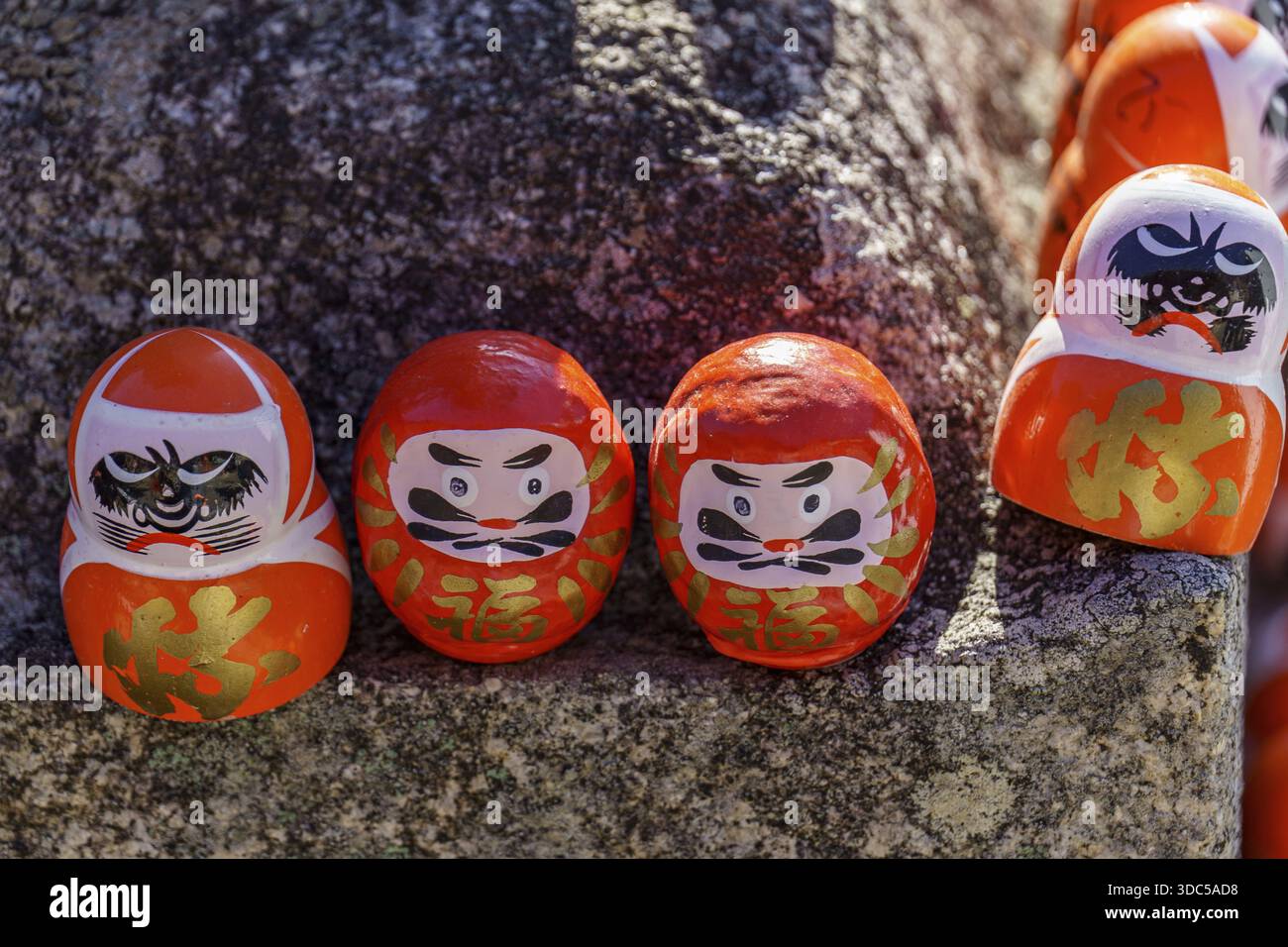 Set di figure Daruma su una pietra con caratteristiche facciali, Osaka, Giappone Foto Stock