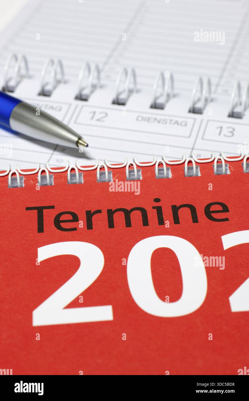 Calendario fotografato in verticale con penna blu e copertina rossa, diario Foto Stock