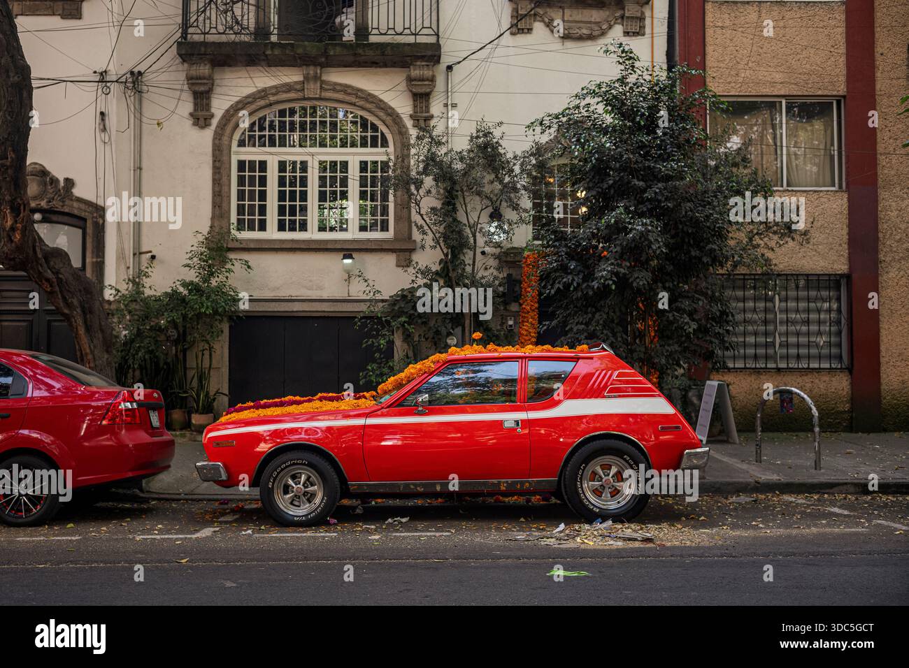 Un AMC Gremlin arancione vintage (costruito tra il 1970 e il 1978) decorato con fiori per le festività Day of the Dead a città del Messico, Roma Norte del Messico Foto Stock