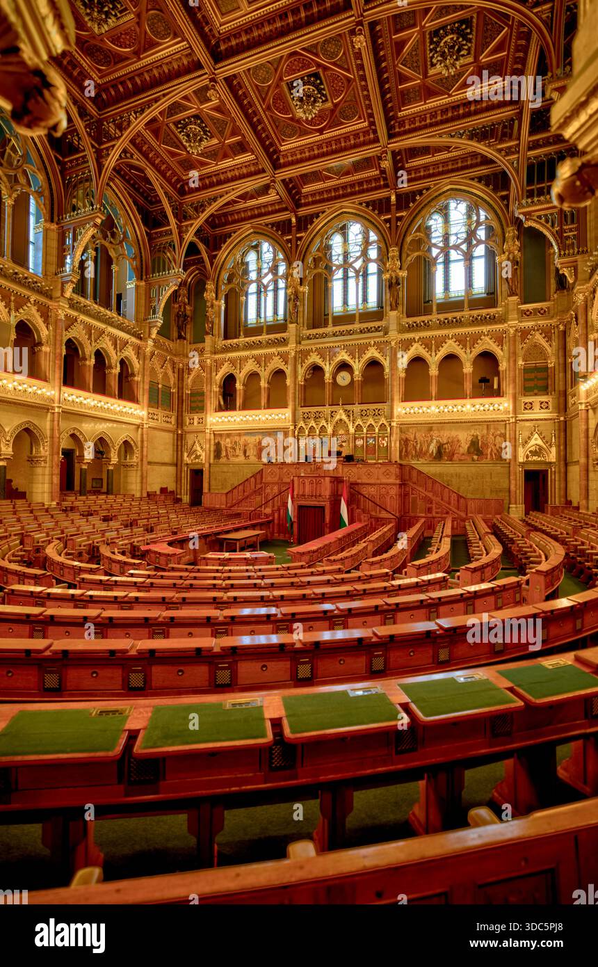 Interno della sala di discussione del Parlamento ungherese, con archi neogotici, posti a sedere in legno a più livelli e una sala legislativa decorata. Foto Stock