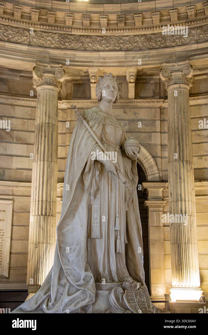 La statua in marmo della regina Vittoria all'interno della sala principale del Victoria Memorial Hall è un simbolo solenne dell'autorità imperiale, della storia e del colon Foto Stock