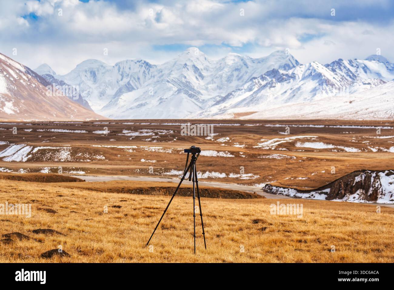 Fotocamera con treppiede in piedi su una natura selvaggia dorata con la catena montuosa Tian Shan in autunno nella remota valle di Sary Jaz, Kirghizistan Foto Stock