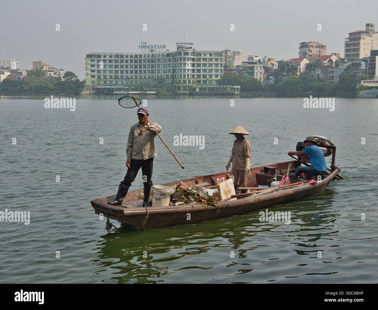 hanoi-Vietnam-10 agosto 2019, i lavoratori ambientali su una barca rimuovono la spazzatura e l'inquinamento da un lago urbano in una città del sud-est asiatico, mettendo in evidenza lo Foto Stock