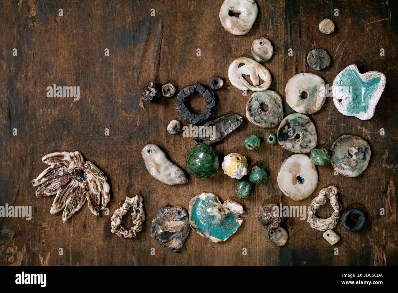 Varie perle di ceramica fatte a mano. Hobby, montaggio gioielli, gioielli fai da te. Idea di officina. Sfondo in legno scuro, vista dall'alto, spazio per copie Foto Stock