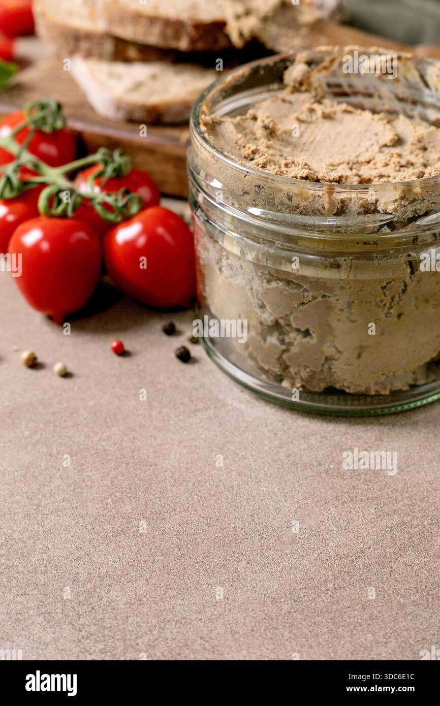 Fette di pane fatte in casa al fegato in vaso di vetro con pomodori ciliegini freschi. Antipasto gourmet con ingredienti naturali. Sfondo a trama rustica. Foto Stock